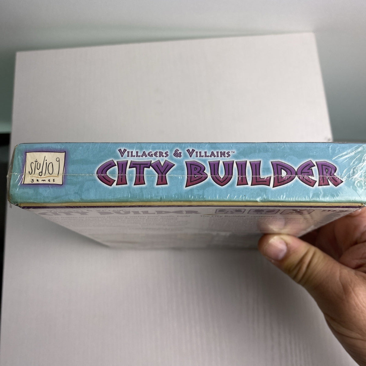 Studio 9 Games Villagers & Villains City Builder tabletop game expansion box in protective wrap