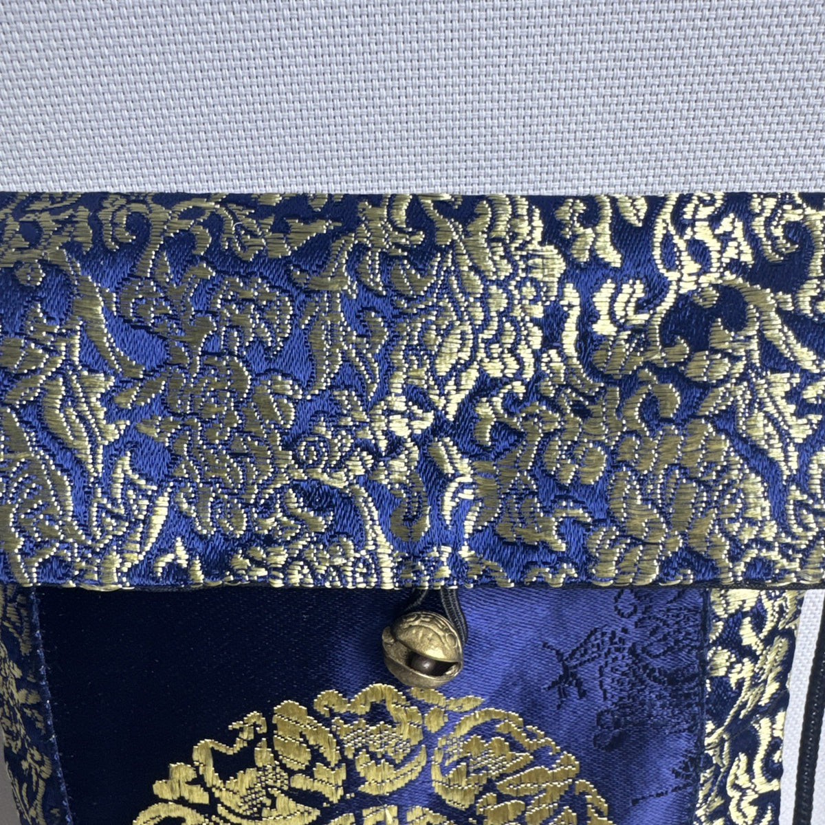 Chinese cobalt blue and gold silk brocade neck pouch featuring a Shou longevity medallion and brass bell toggle