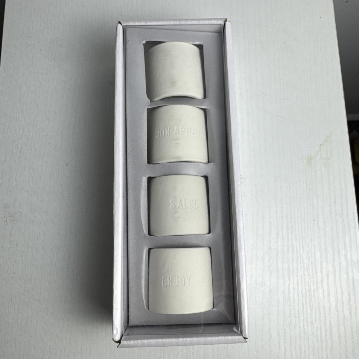 Santa Barbara Design Studio set of four white ceramic napkin rings debossed with entertaining phrases in original box