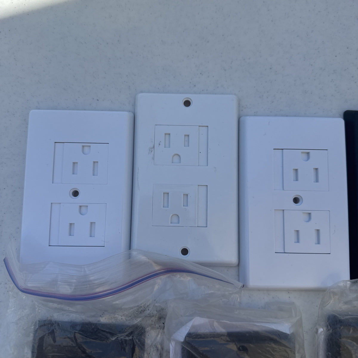 Set of 15 black and white self-closing child safety outlet cover wall plates.