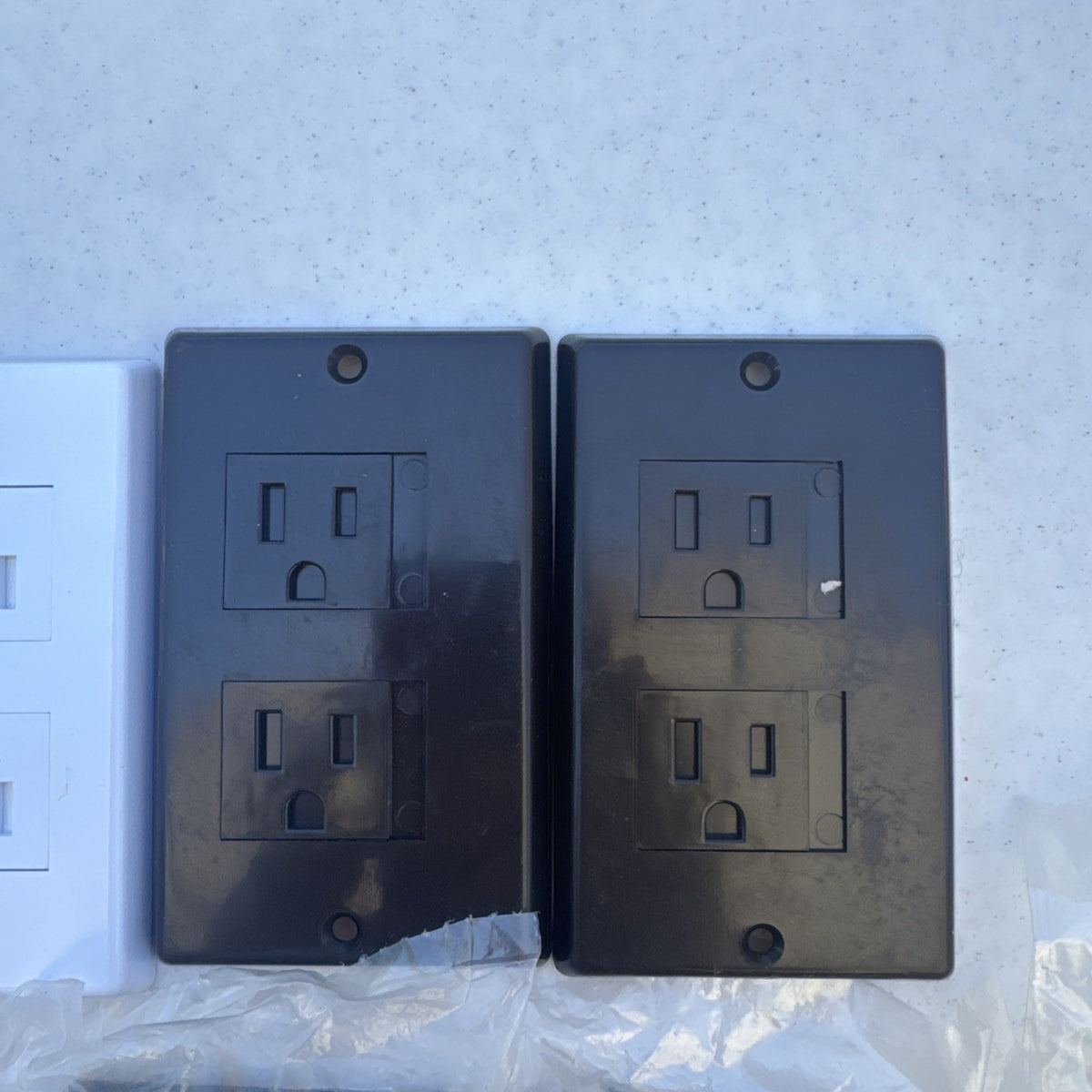 Set of 15 black and white self-closing child safety outlet cover wall plates.