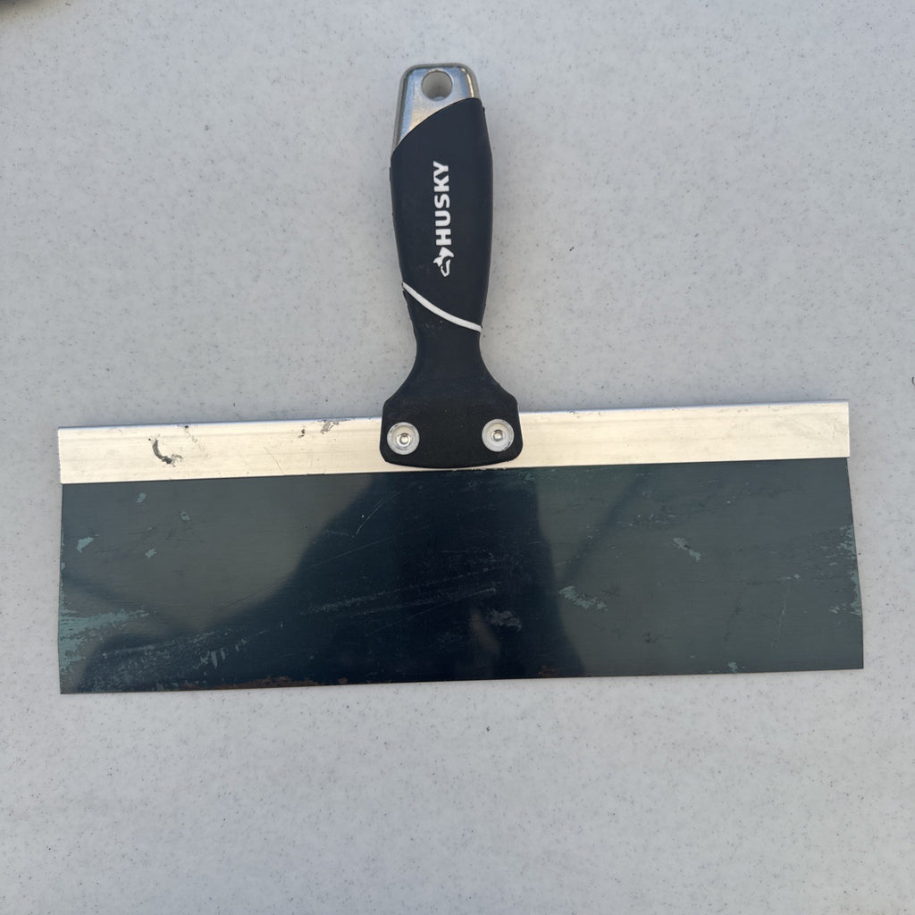 Husky 12 inch blue spring steel taping knife featuring soft grip handle and integrated hammer end