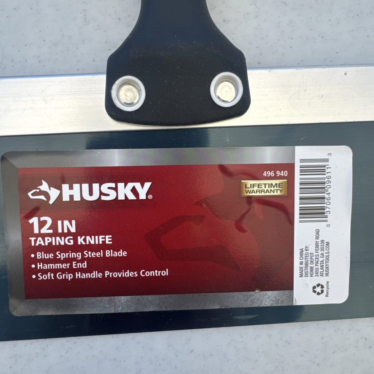 Husky 12 inch blue spring steel taping knife featuring soft grip handle and integrated hammer end