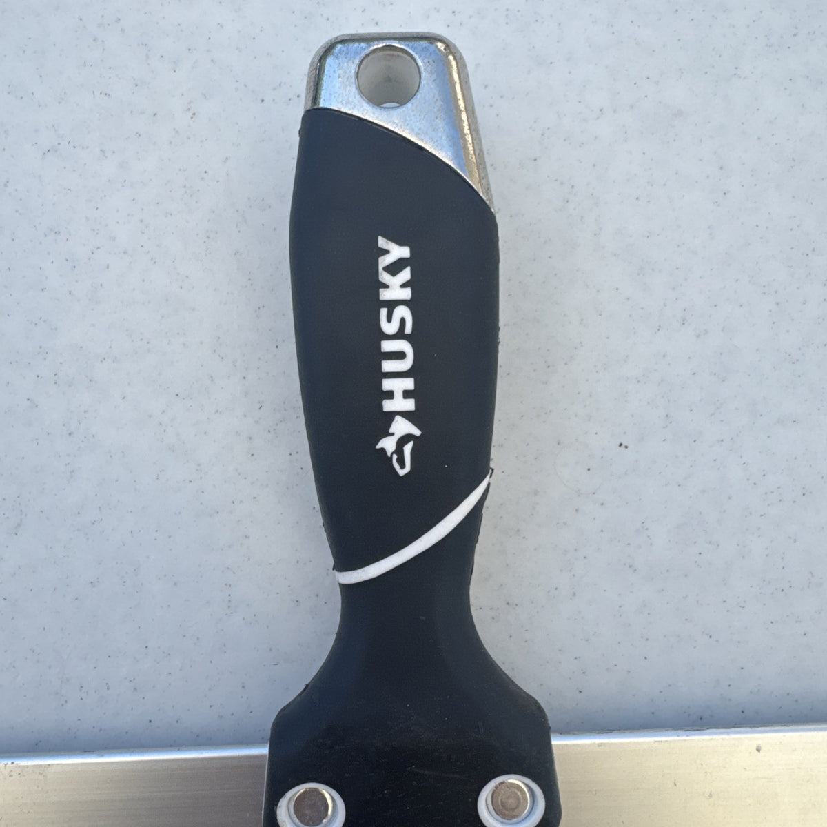 Husky 12 inch blue spring steel taping knife featuring soft grip handle and integrated hammer end