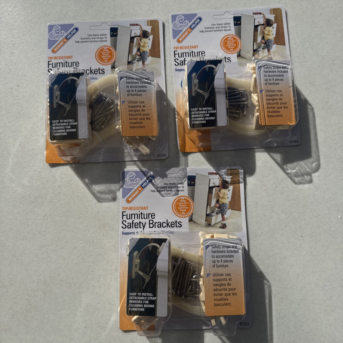 Three sealed packages of Mommy's Helper tip-resistant furniture safety brackets model 02263.