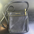 Michael Kors black pebbled leather flat crossbody bag with gold hardware and front zip pocket