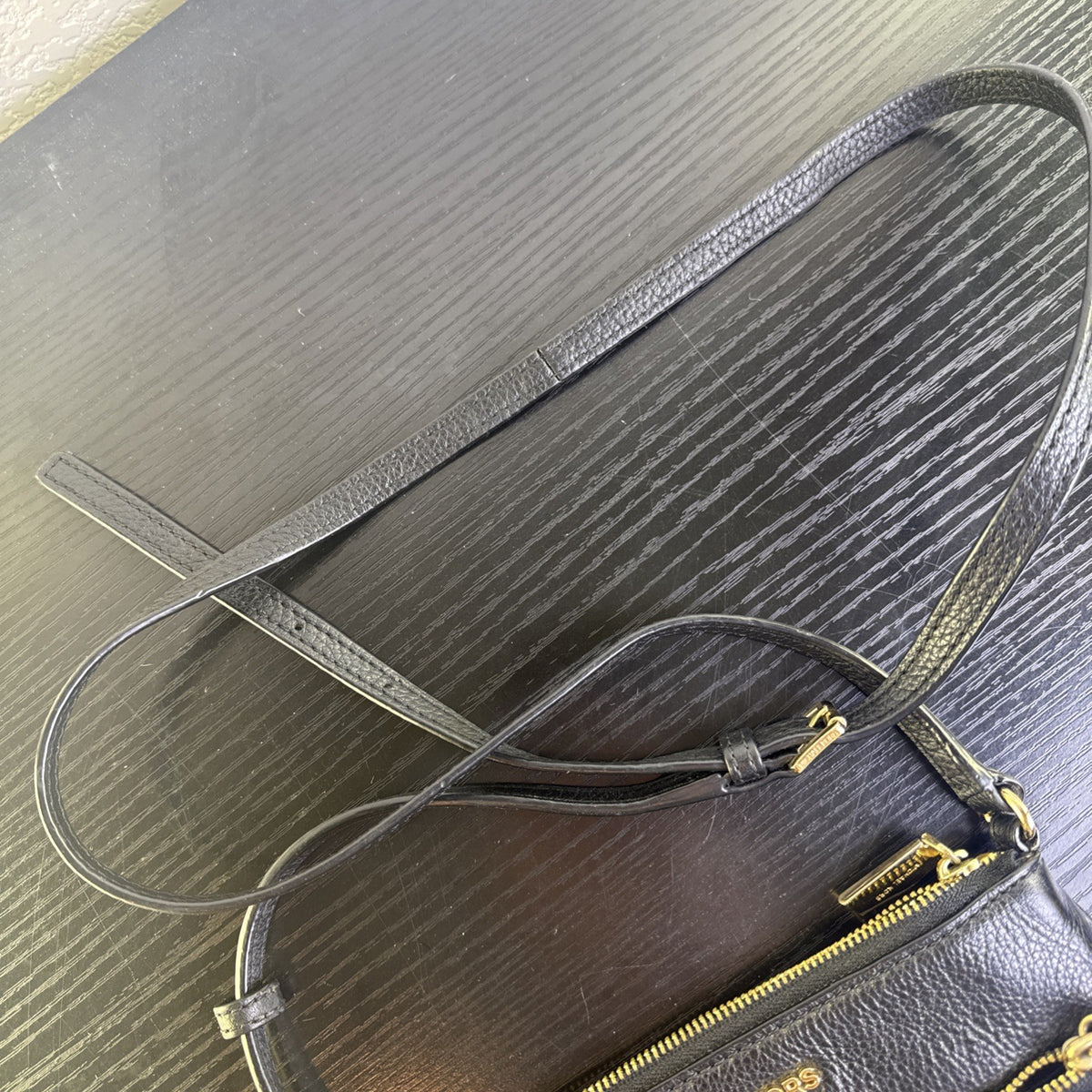 Michael Kors black pebbled leather flat crossbody bag with gold hardware and front zip pocket