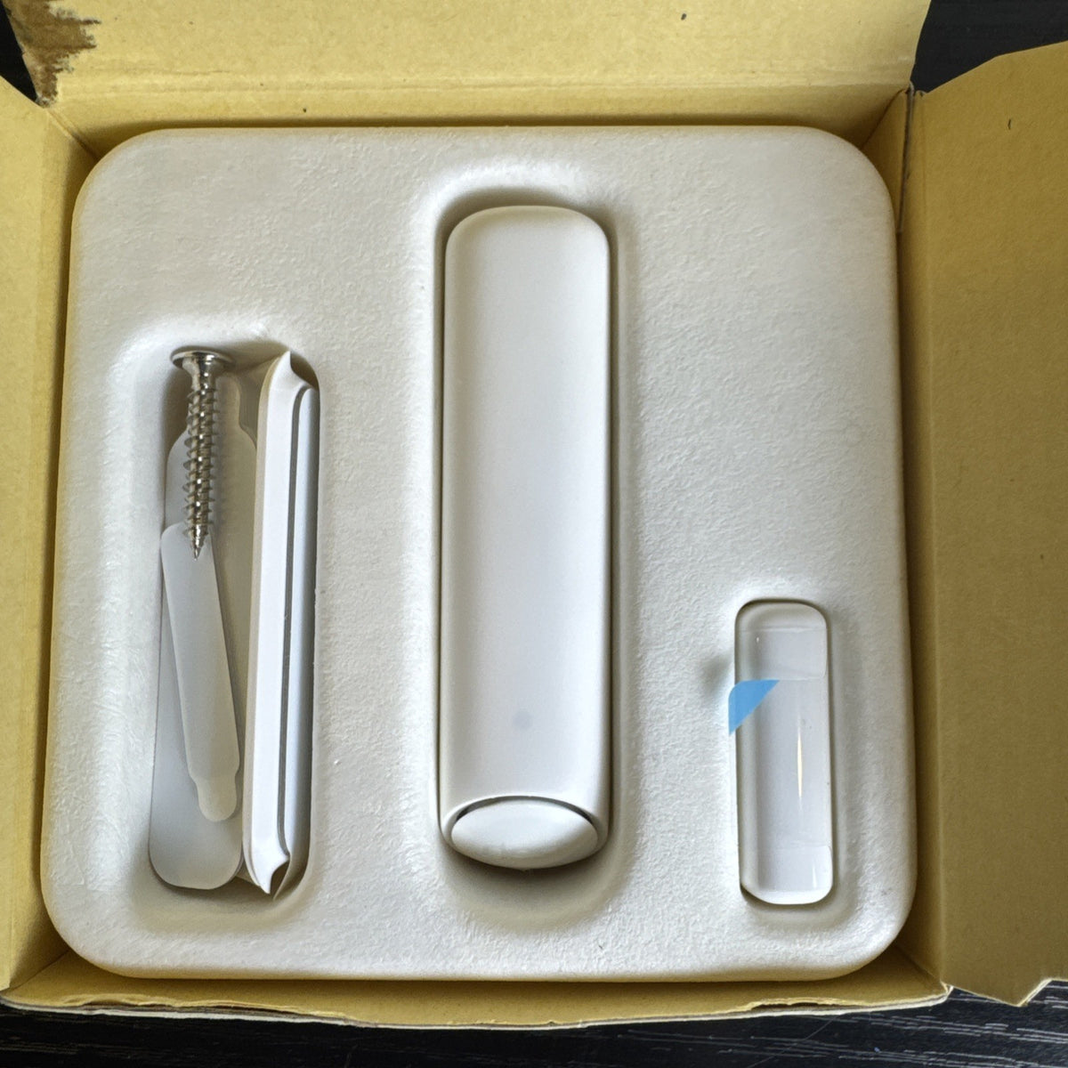 Open box Google Nest Detect H1100WES wireless door and window sensor showing its sleek white design.