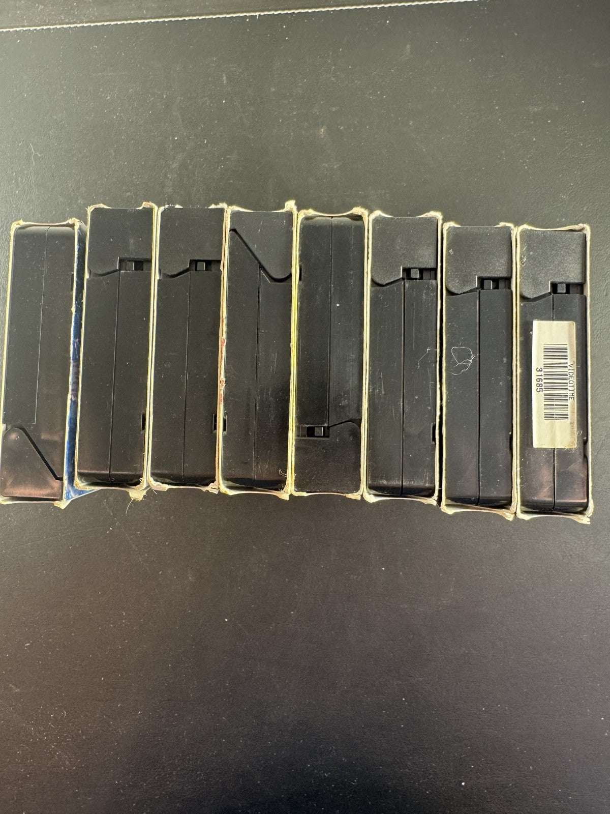 Collection of 8 vintage action movie VHS tapes including Rush Hour, Cliffhanger, and The Fugitive.