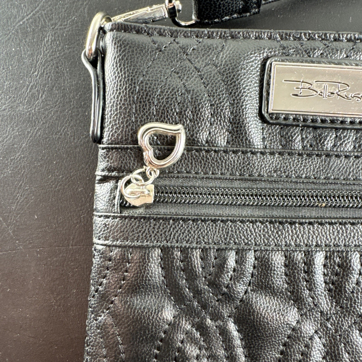 Bella Russo black quilted faux leather crossbody bag with silver-tone heart zipper pull.