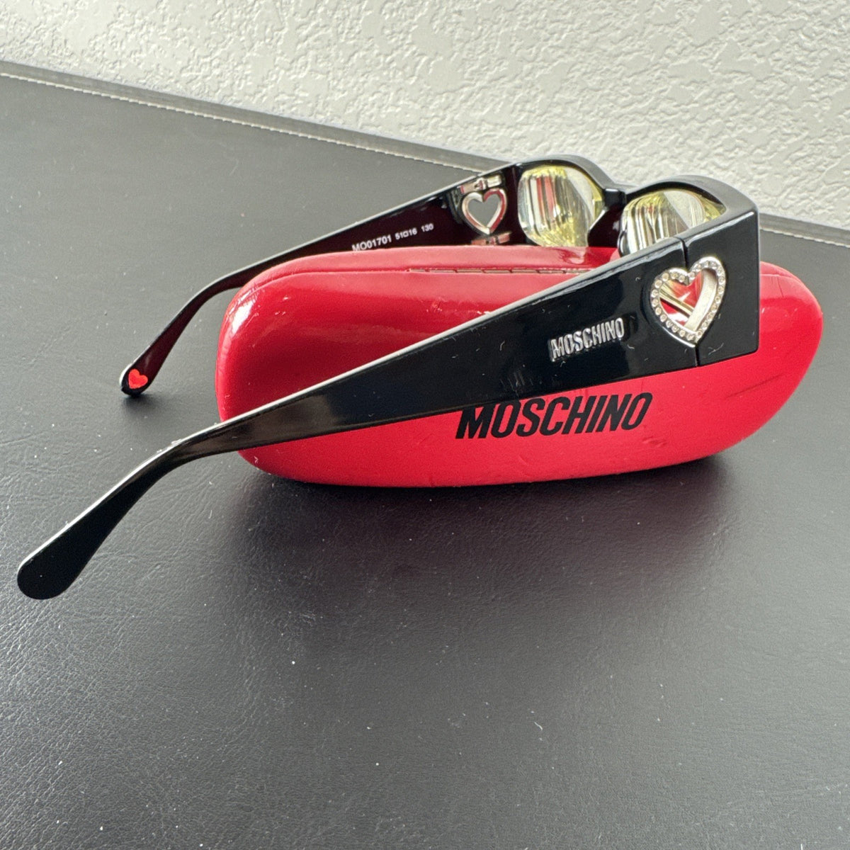 Vintage Moschino MO01701 black acetate eyeglass frames with rhinestone heart cutouts on temple arms.
