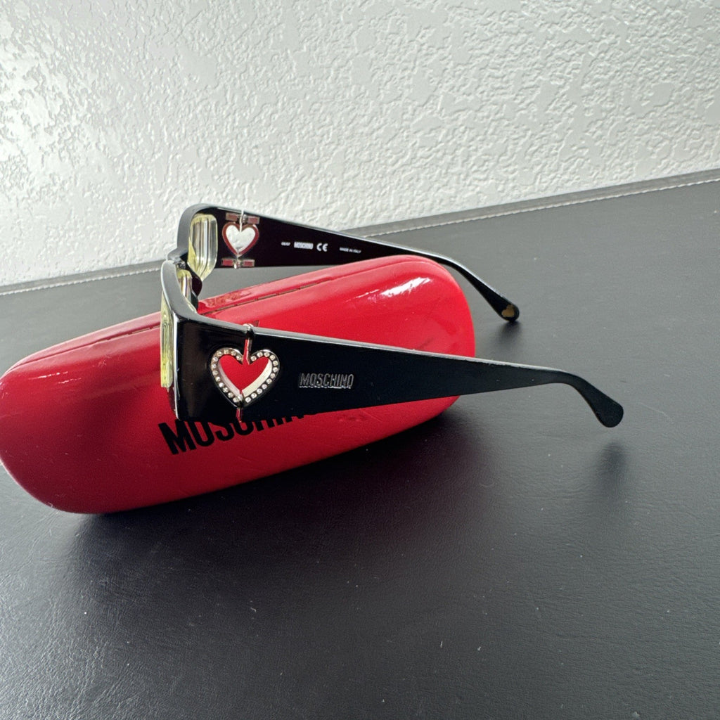 Vintage Moschino MO01701 black acetate eyeglass frames with rhinestone heart cutouts on temple arms.
