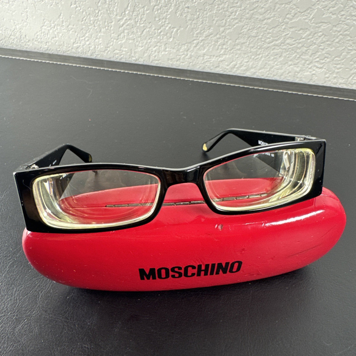 Vintage Moschino MO01701 black acetate eyeglass frames with rhinestone heart cutouts on temple arms.