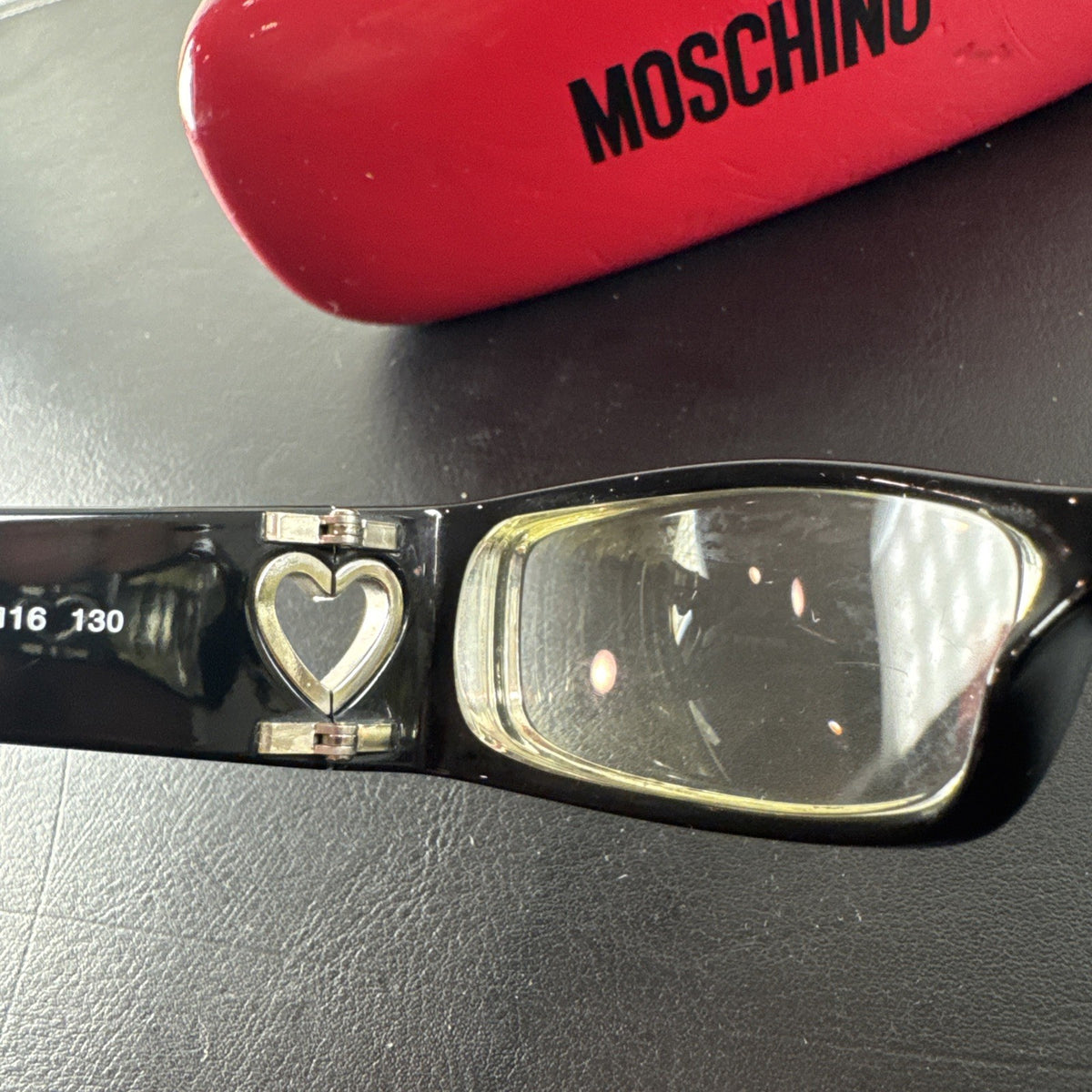 Vintage Moschino MO01701 black acetate eyeglass frames with rhinestone heart cutouts on temple arms.