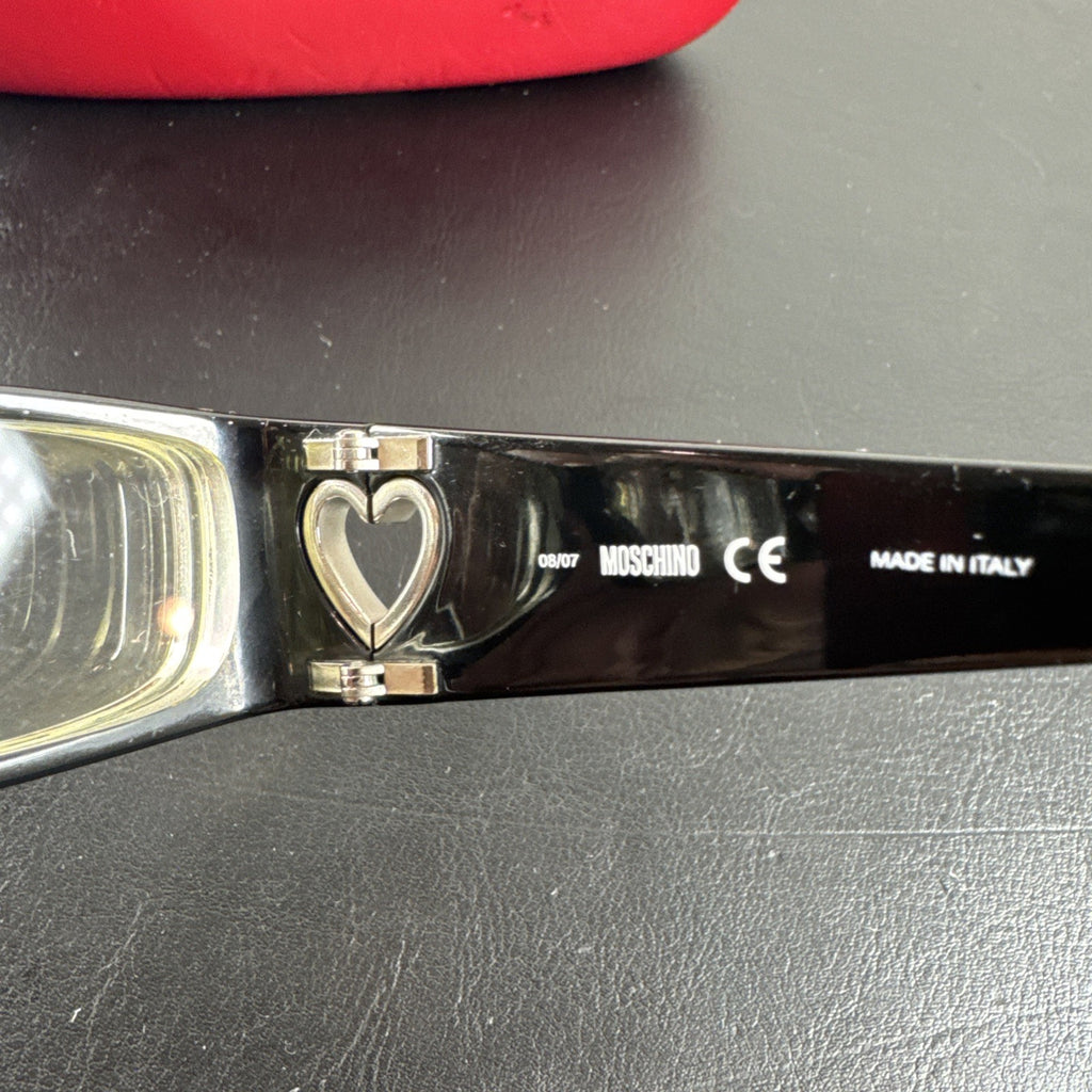 Vintage Moschino MO01701 black acetate eyeglass frames with rhinestone heart cutouts on temple arms.