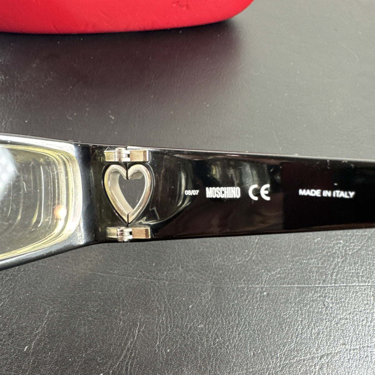 Vintage Moschino MO01701 black acetate eyeglass frames with rhinestone heart cutouts on temple arms.