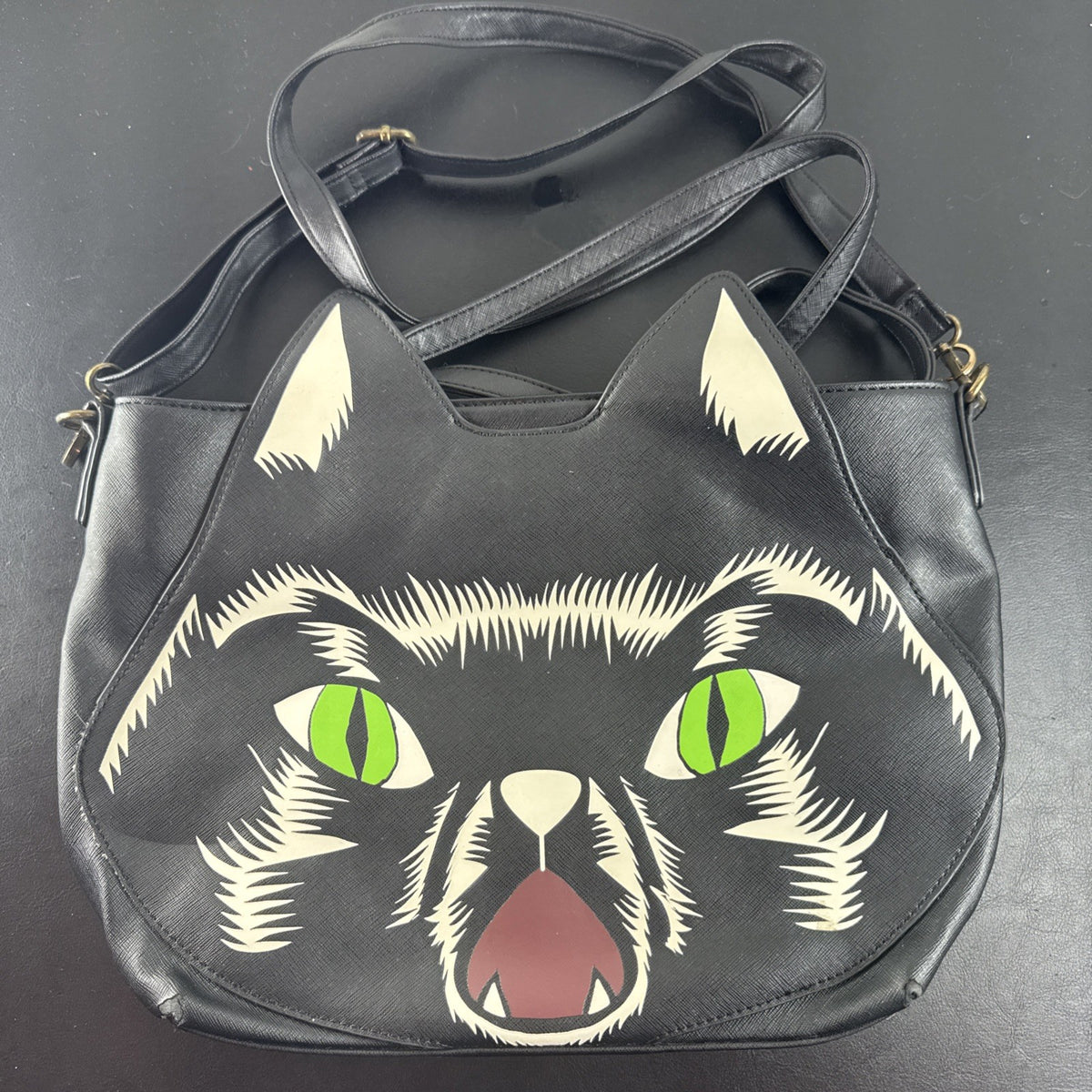 Loungefly Disney Hocus Pocus Thackery Binx black faux leather tote bag showing die-cut cat ears and green eyes.