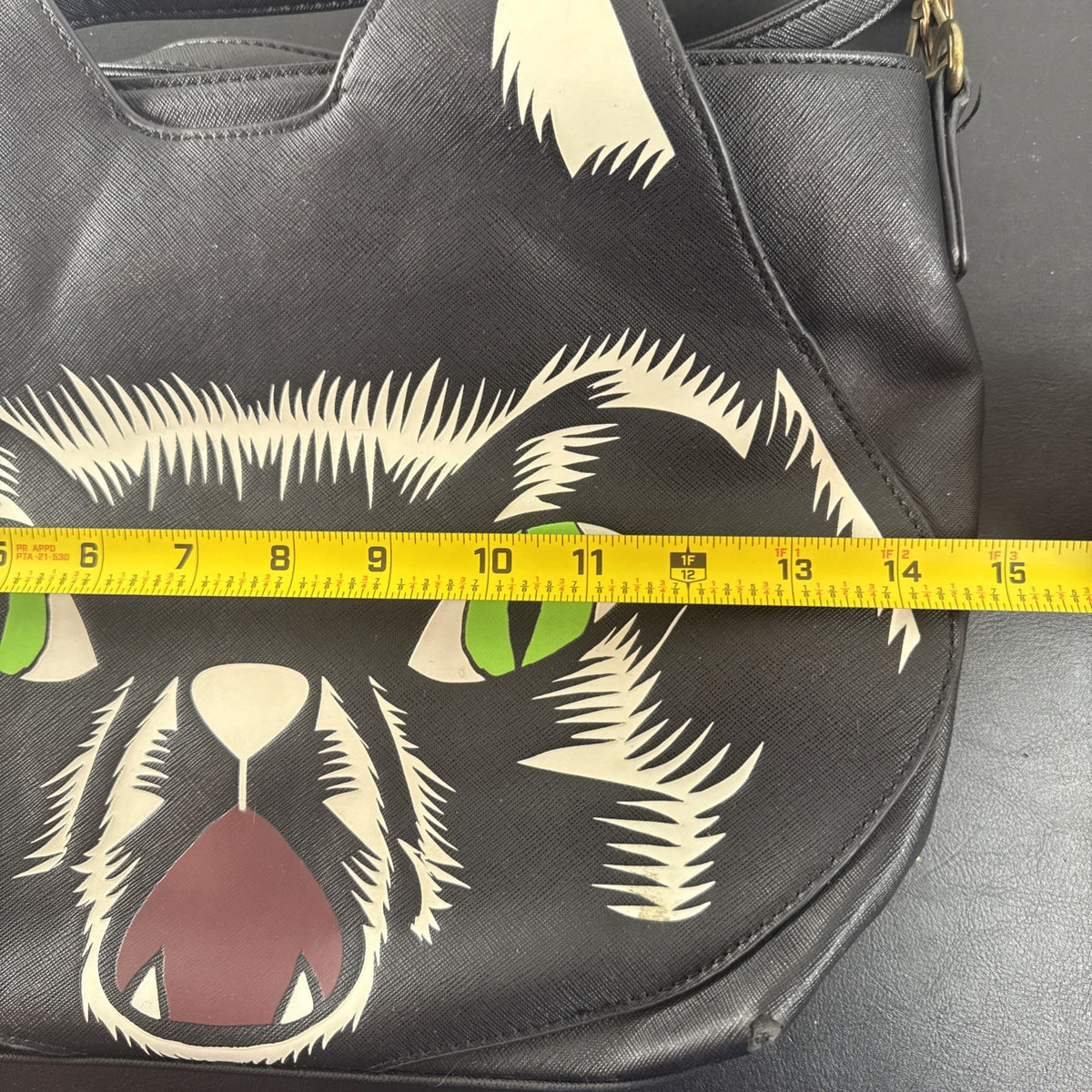 Loungefly Disney Hocus Pocus Thackery Binx black faux leather tote bag showing die-cut cat ears and green eyes.