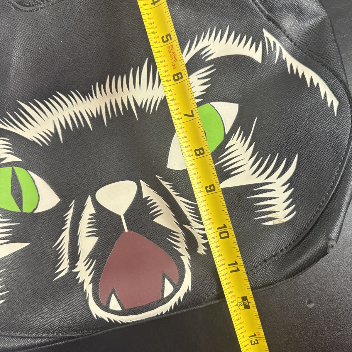 Loungefly Disney Hocus Pocus Thackery Binx black faux leather tote bag showing die-cut cat ears and green eyes.