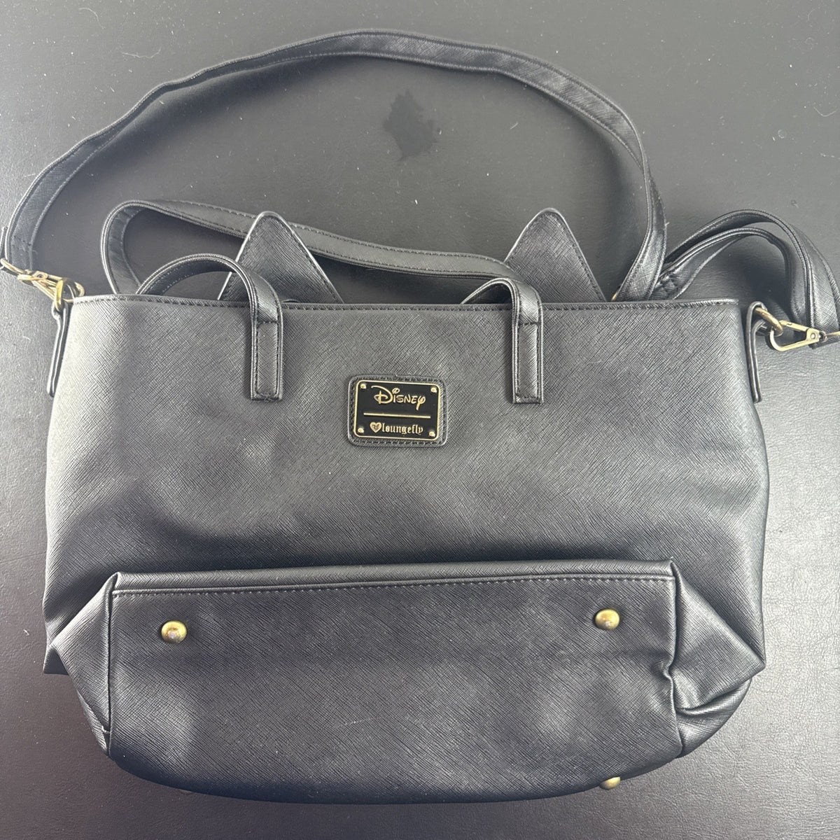 Loungefly Disney Hocus Pocus Thackery Binx black faux leather tote bag showing die-cut cat ears and green eyes.