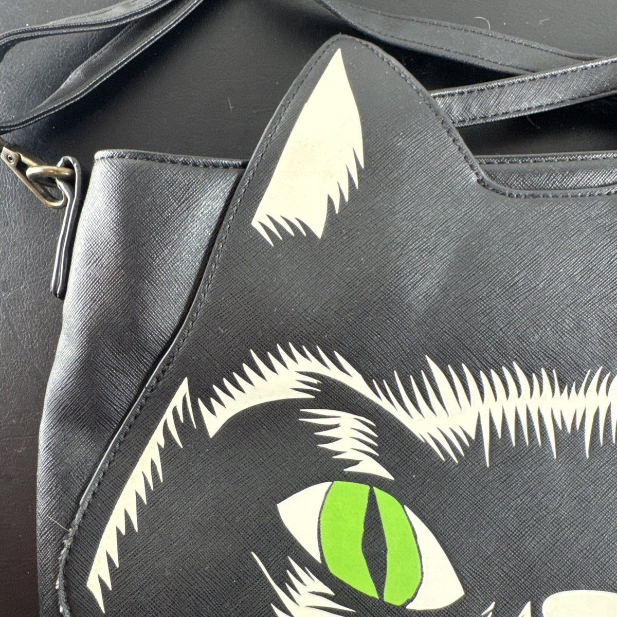 Loungefly Disney Hocus Pocus Thackery Binx black faux leather tote bag showing die-cut cat ears and green eyes.