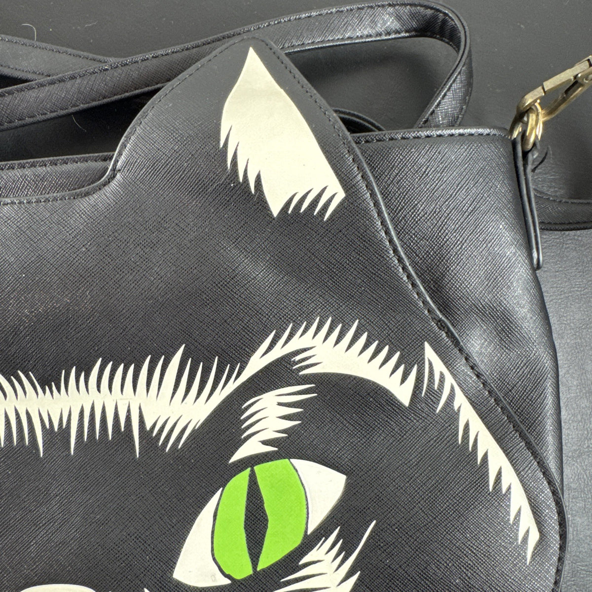 Loungefly Disney Hocus Pocus Thackery Binx black faux leather tote bag showing die-cut cat ears and green eyes.