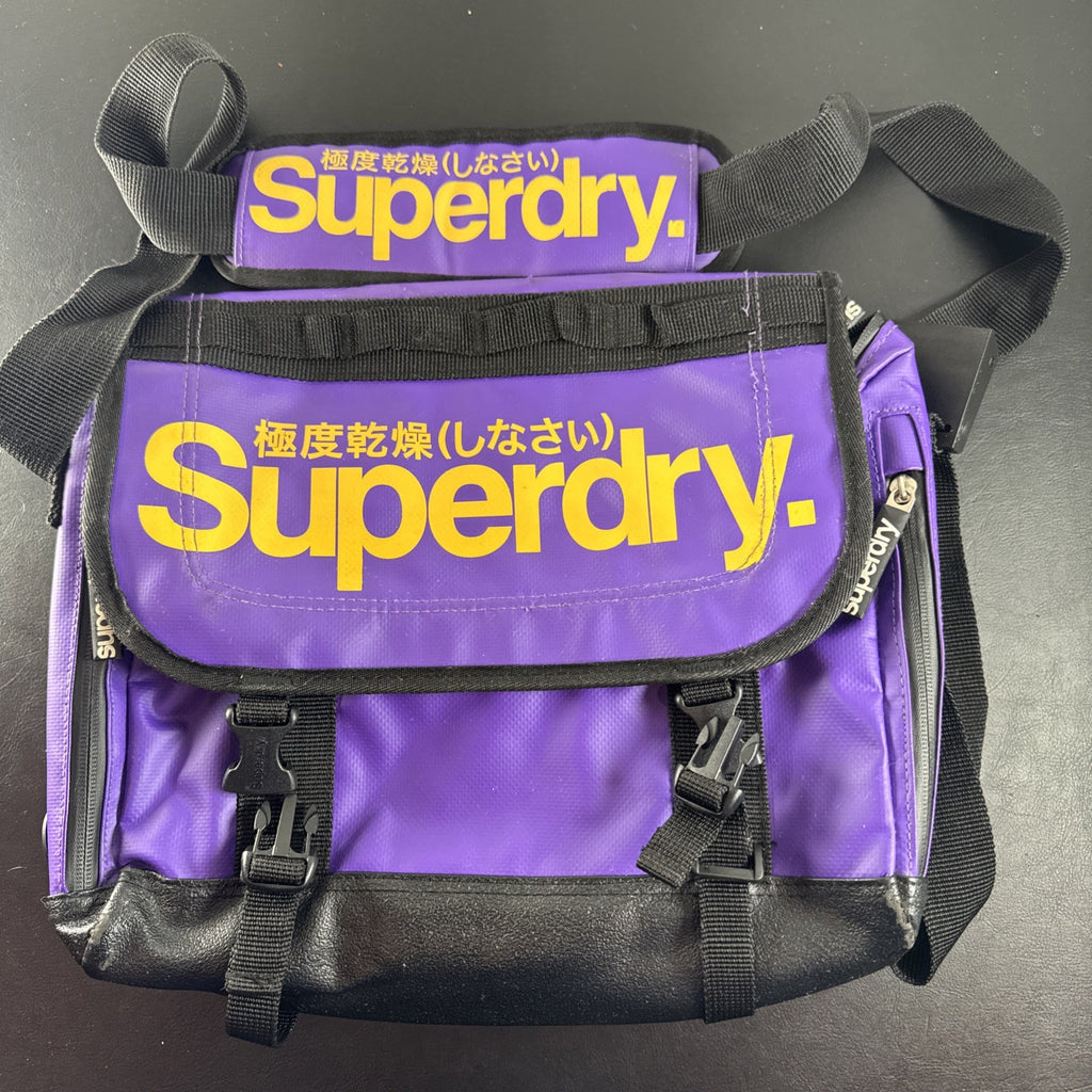 Purple and yellow Superdry tarp messenger bag with bold logo spellout and padded shoulder strap.