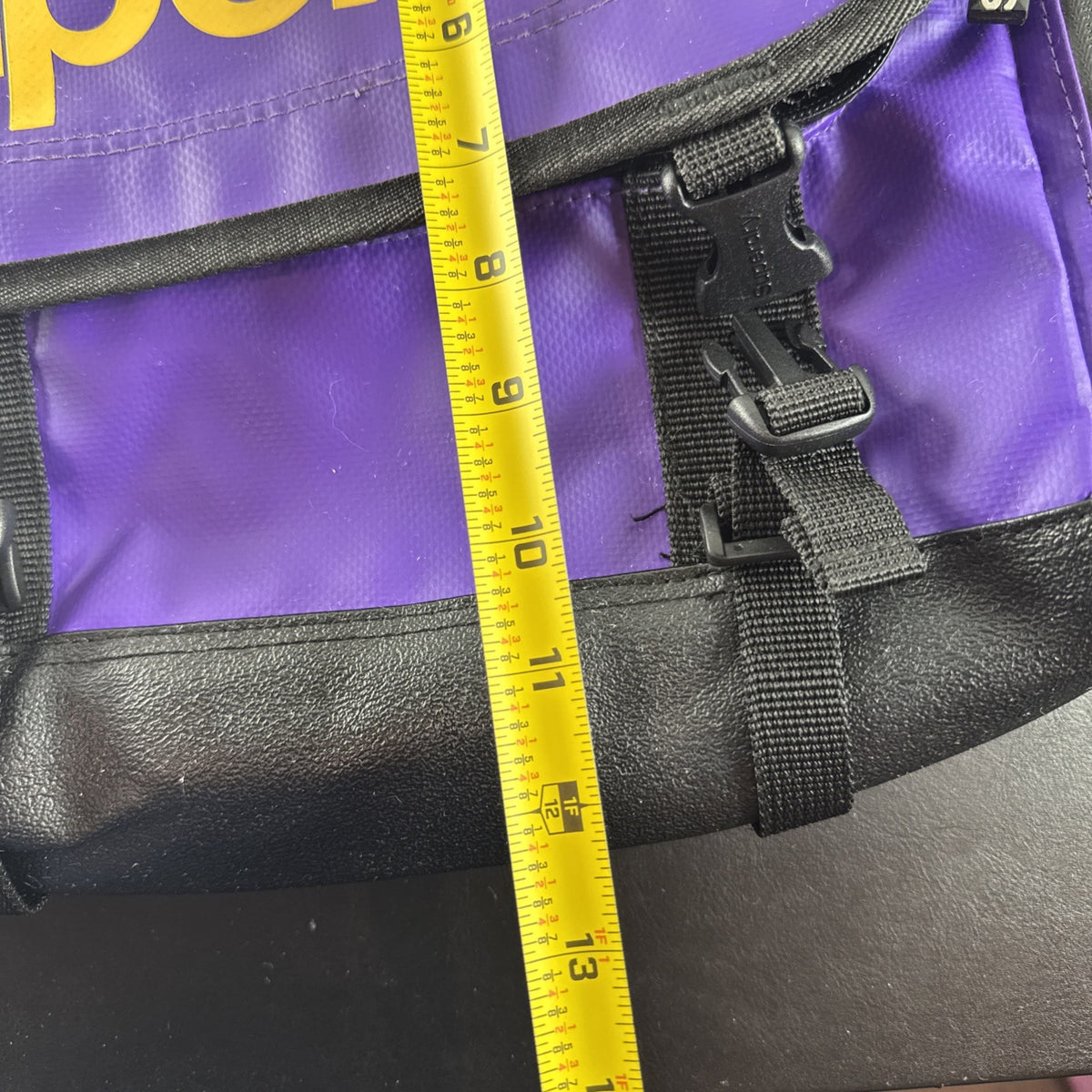 Purple and yellow Superdry tarp messenger bag with bold logo spellout and padded shoulder strap.