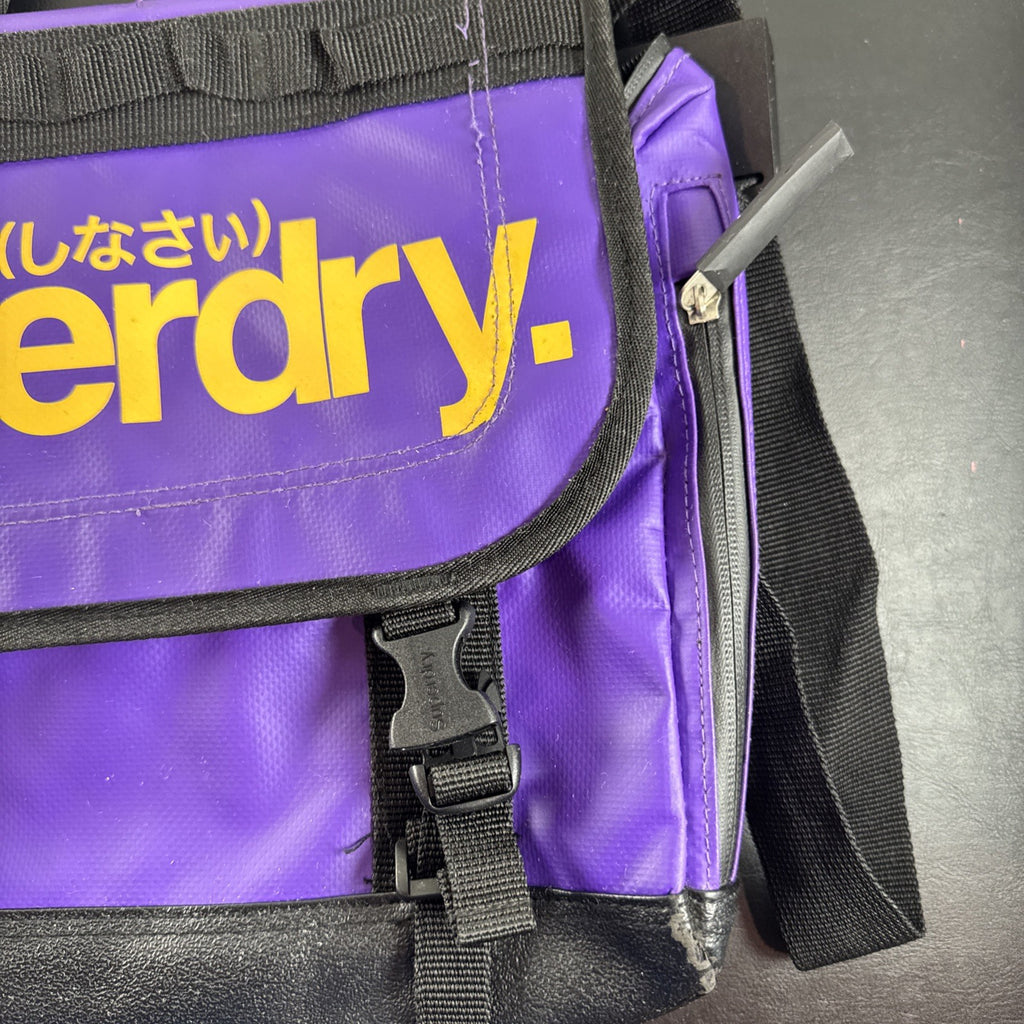 Purple and yellow Superdry tarp messenger bag with bold logo spellout and padded shoulder strap.