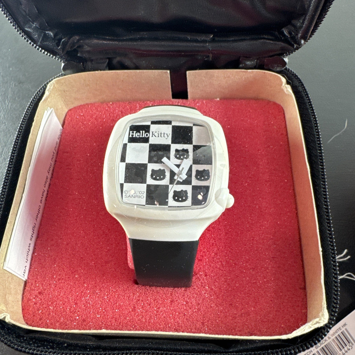 2002 Sanrio Hello Kitty watch with black and white checkerboard face, original zippered case, and tags.