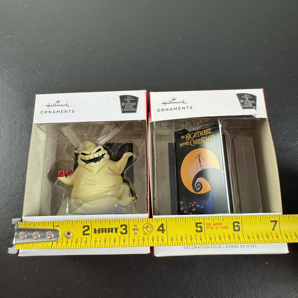 Set of two Hallmark Nightmare Before Christmas ornaments featuring Oogie Boogie holding dice and a retro VHS tape box.