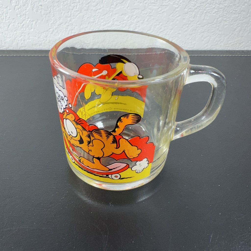 Vintage 1978 McDonald's clear glass mug featuring Garfield on a skateboard pulled by Odie.