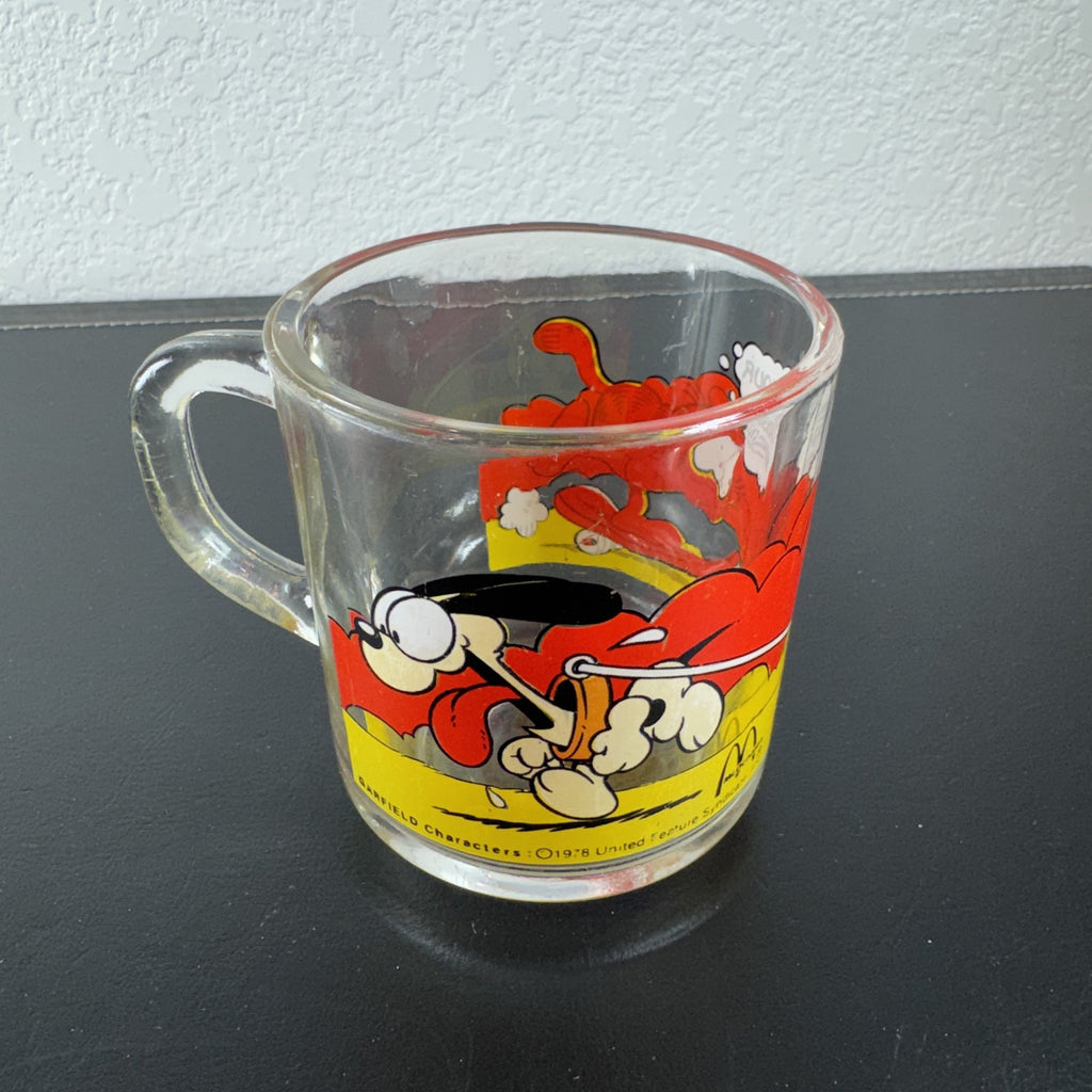 Vintage 1978 McDonald's clear glass mug featuring Garfield on a skateboard pulled by Odie.