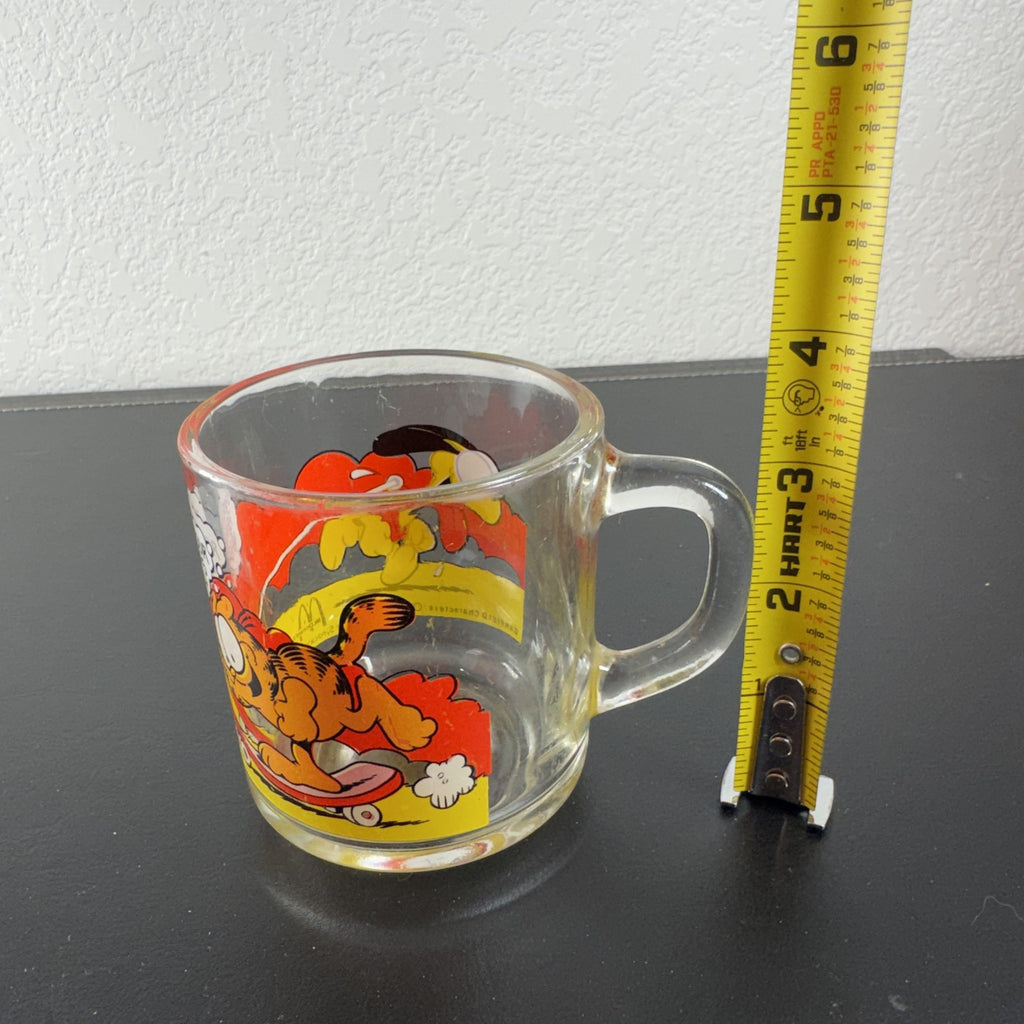 Vintage 1978 McDonald's clear glass mug featuring Garfield on a skateboard pulled by Odie.