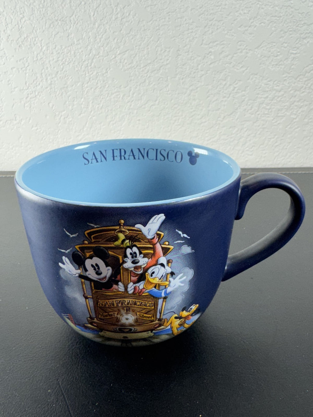 Disney navy blue ceramic mug featuring Mickey Mouse and friends riding a San Francisco cable car