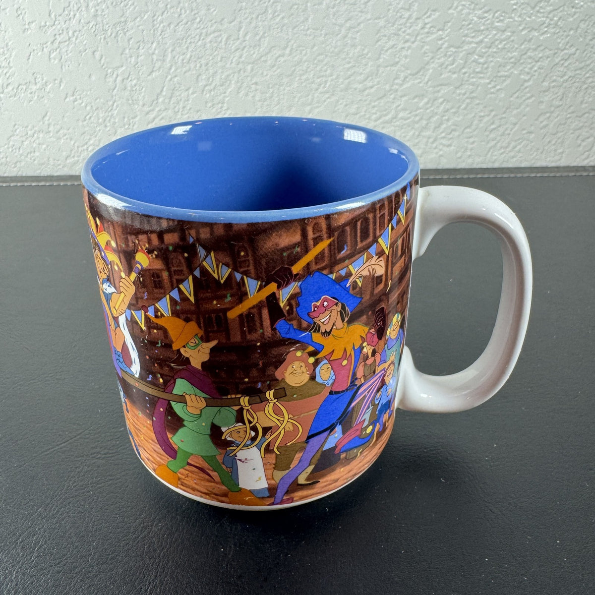 Vintage Disney Hunchback of Notre Dame ceramic mug with Festival of Fools artwork and blue interior.