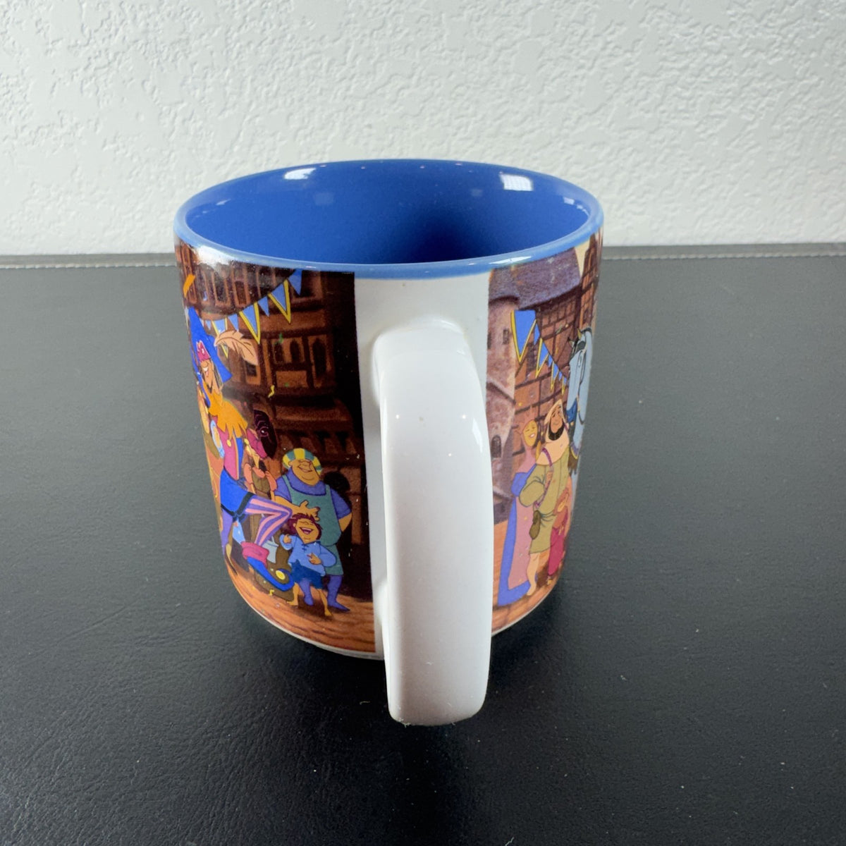 Vintage Disney Hunchback of Notre Dame ceramic mug with Festival of Fools artwork and blue interior.