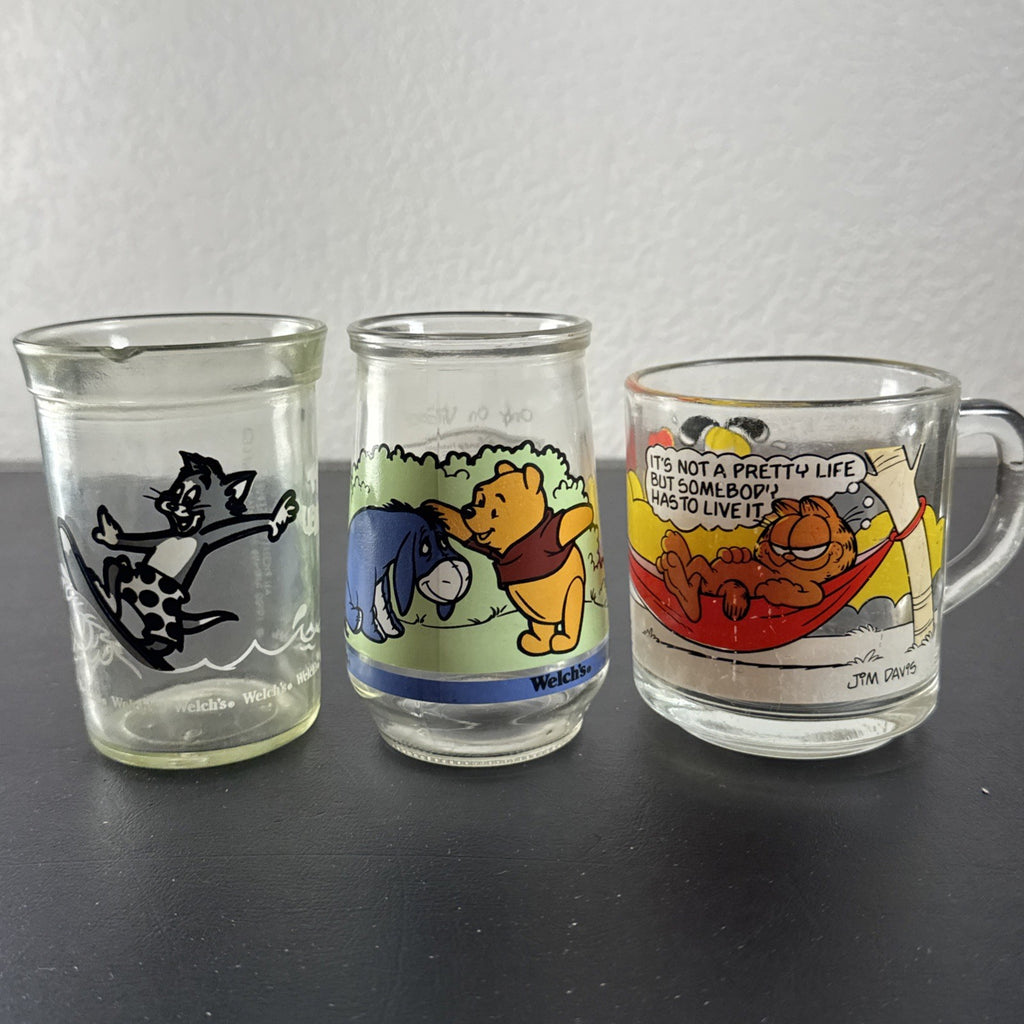 Set of three vintage cartoon promo glasses featuring McDonald's Garfield mug and Welch's jelly jars.