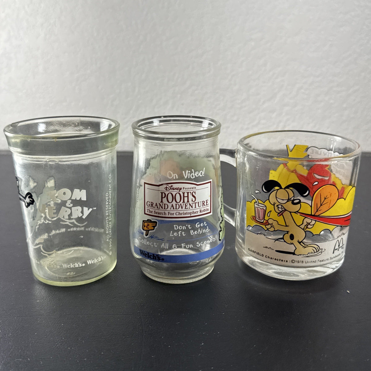 Set of three vintage cartoon promo glasses featuring McDonald's Garfield mug and Welch's jelly jars.
