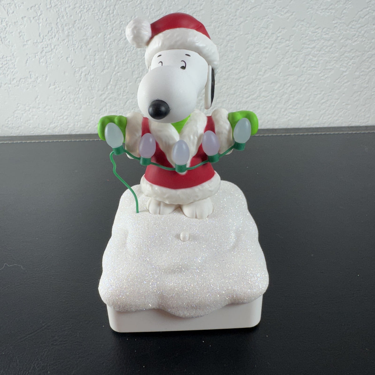 Hallmark Snoopy in Santa suit holding holiday lights on a glittery snow base tabletop figure