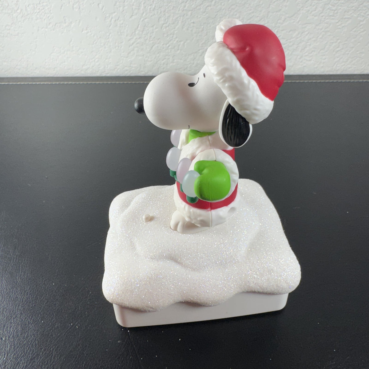Hallmark Snoopy in Santa suit holding holiday lights on a glittery snow base tabletop figure