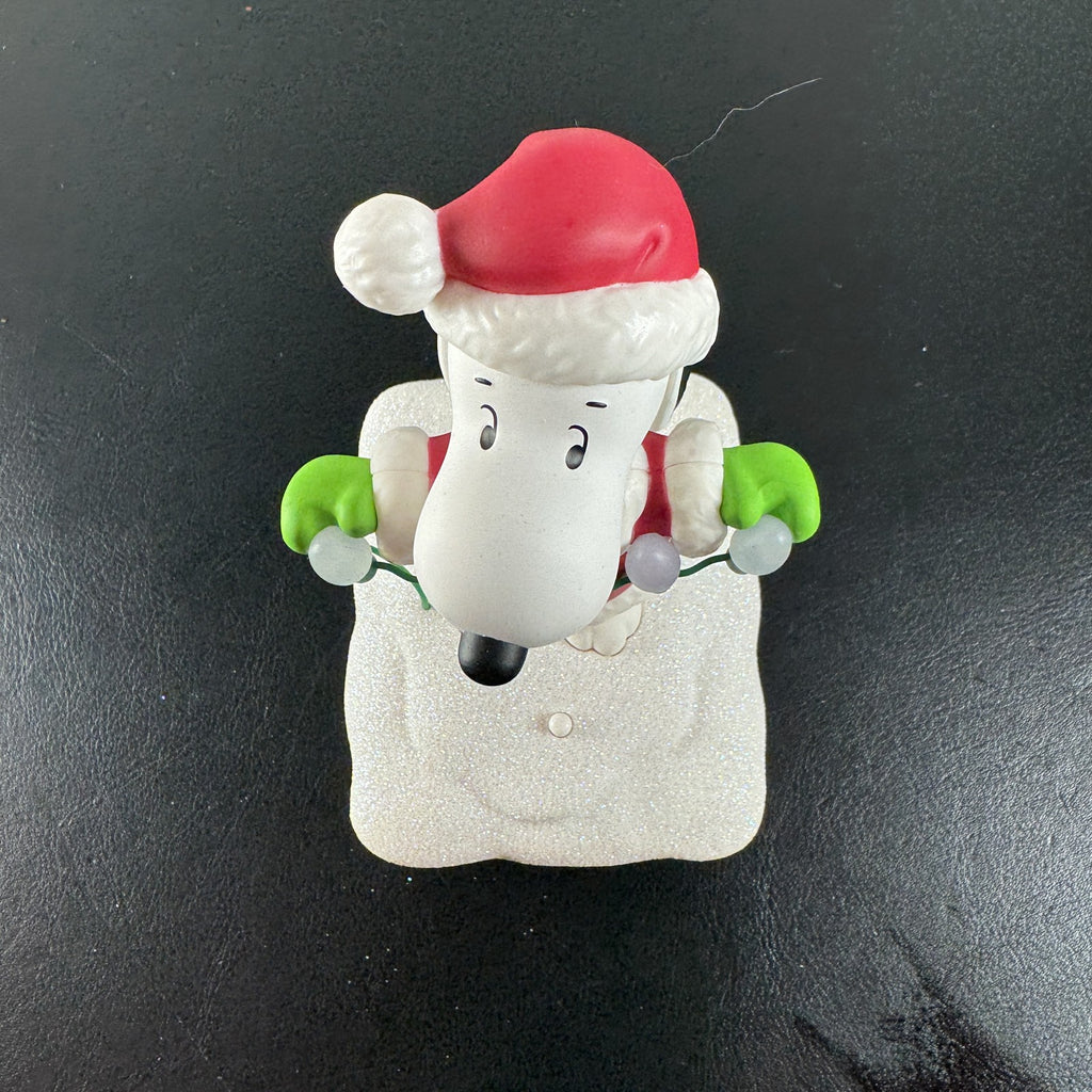 Hallmark Snoopy in Santa suit holding holiday lights on a glittery snow base tabletop figure