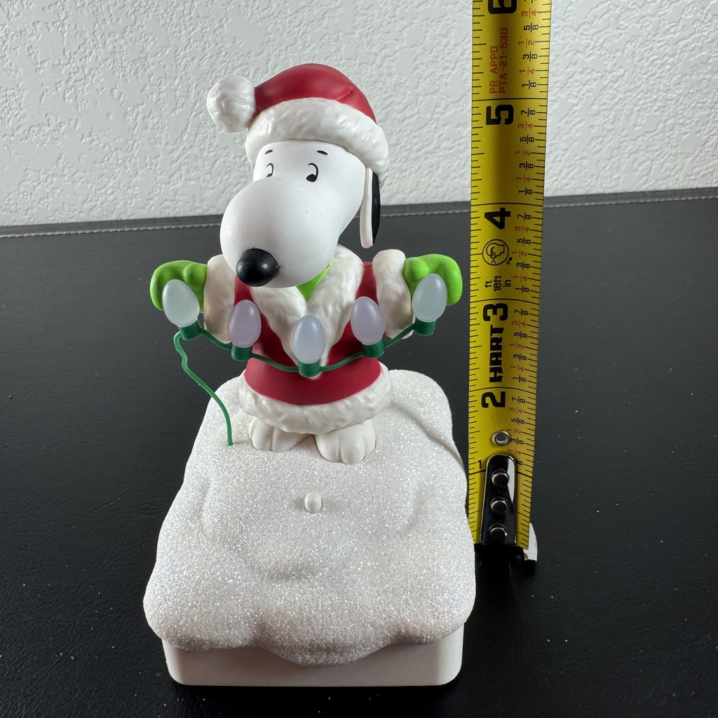 Hallmark Snoopy in Santa suit holding holiday lights on a glittery snow base tabletop figure