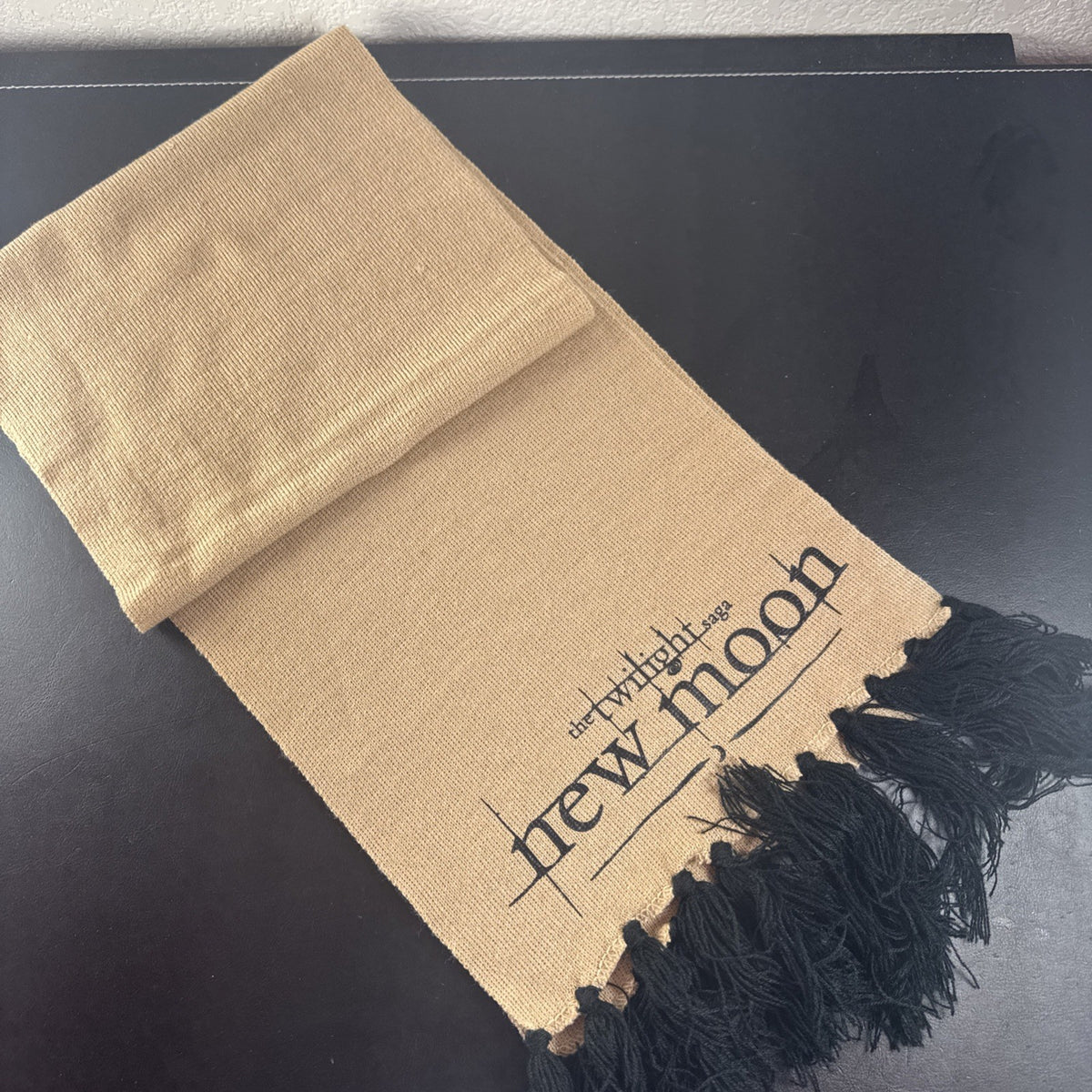 Tan knit Twilight Saga New Moon promo scarf featuring the Cullen family crest and black fringe tassels.