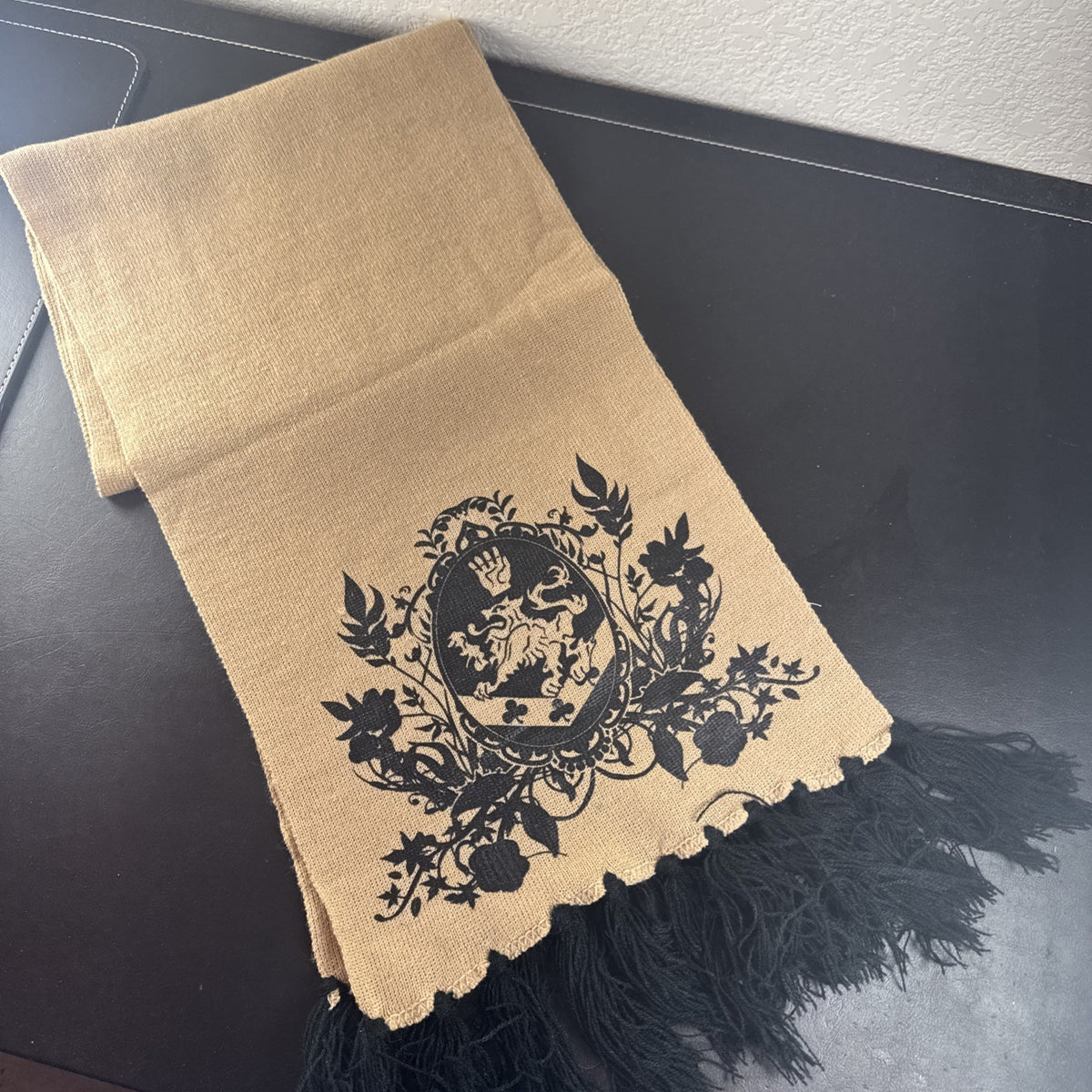 Tan knit Twilight Saga New Moon promo scarf featuring the Cullen family crest and black fringe tassels.
