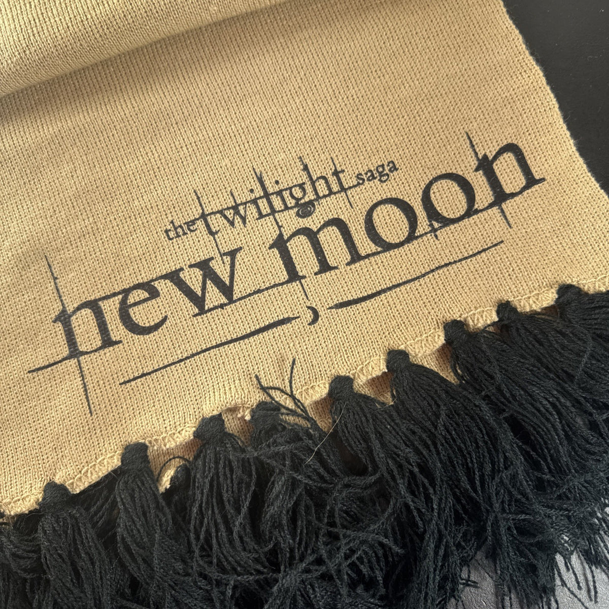 Tan knit Twilight Saga New Moon promo scarf featuring the Cullen family crest and black fringe tassels.