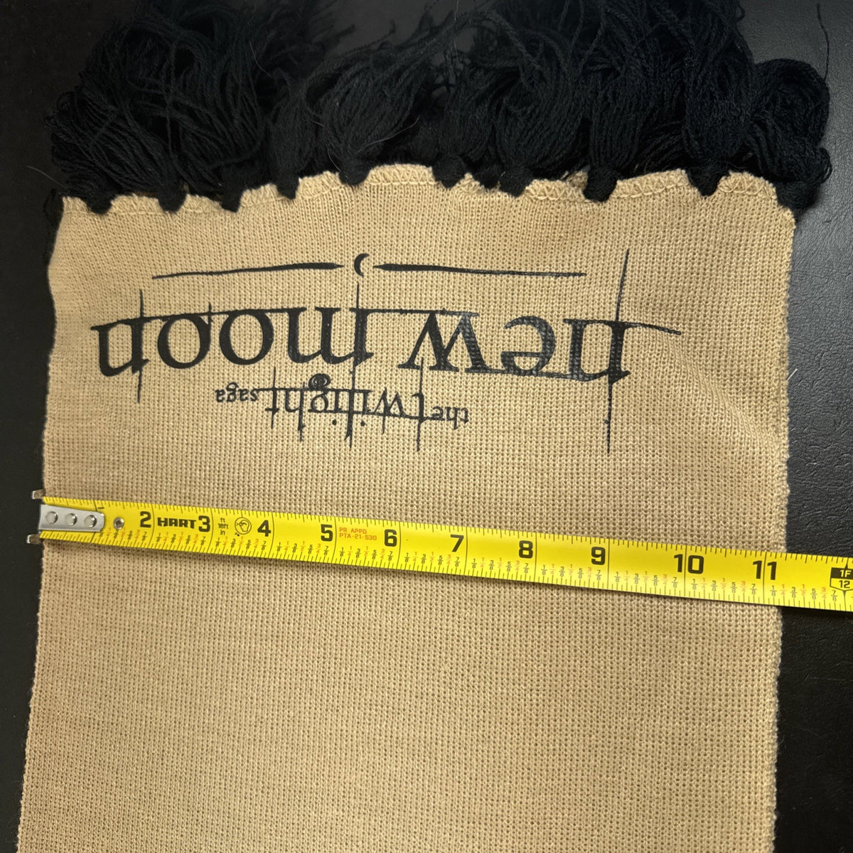 Tan knit Twilight Saga New Moon promo scarf featuring the Cullen family crest and black fringe tassels.