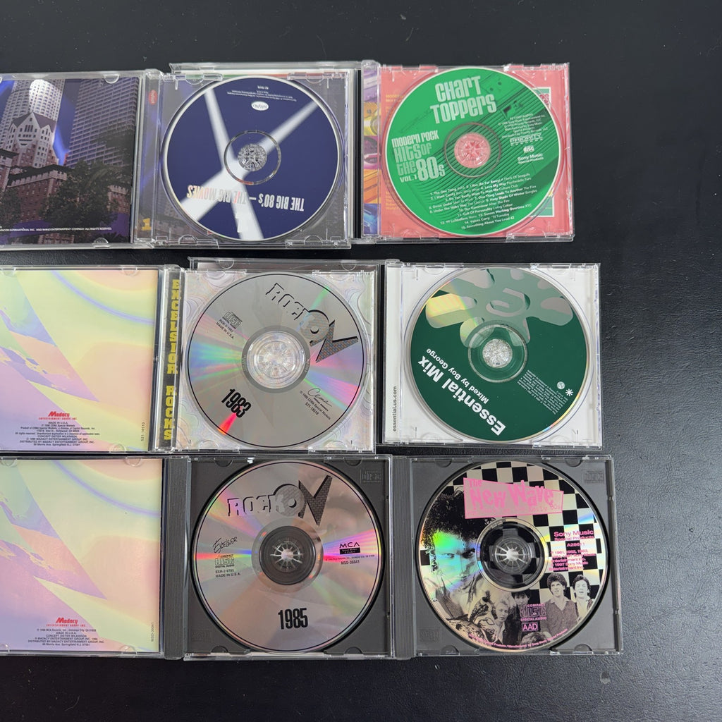 Set of 6 pre-owned 1980s compilation CDs including 80s movie hits and new wave rock collections.