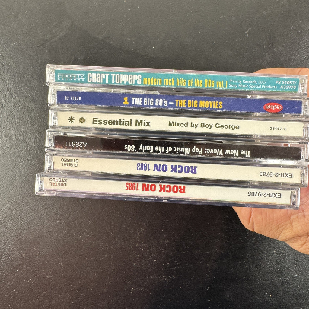 Set of 6 pre-owned 1980s compilation CDs including 80s movie hits and new wave rock collections.