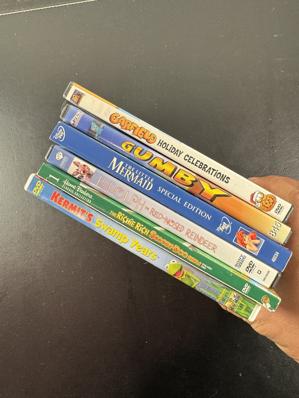Collection of 6 family animation DVDs including Disney's The Little Mermaid, Scooby-Doo, and Garfield in cases.